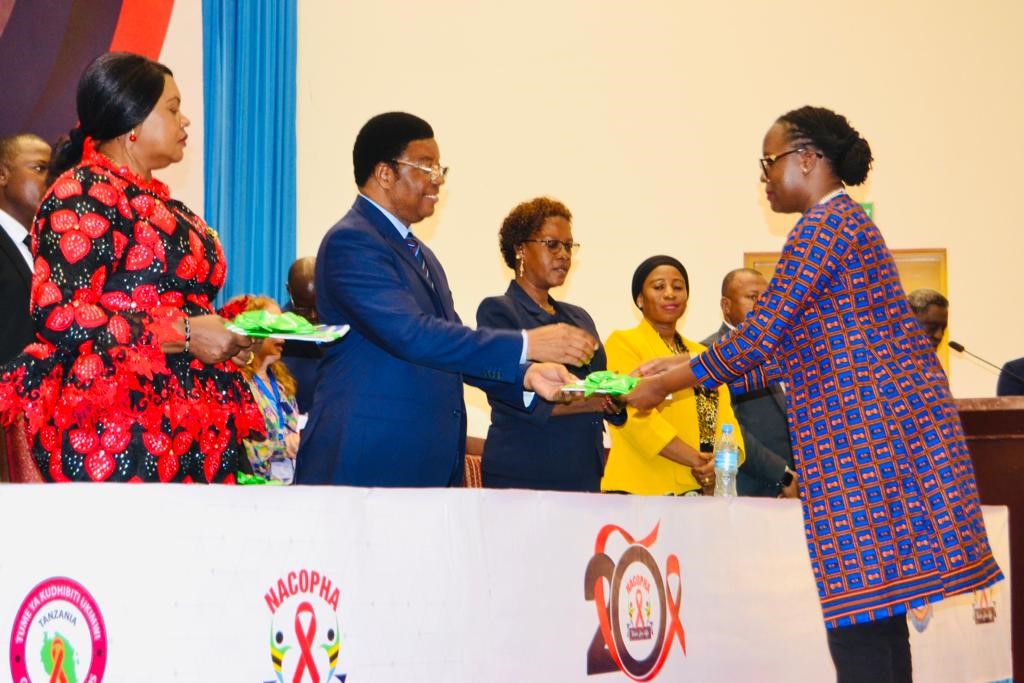 Members receiving recognition at a NACOPHA ceremony, in front of the council's twentieth anniversary banner