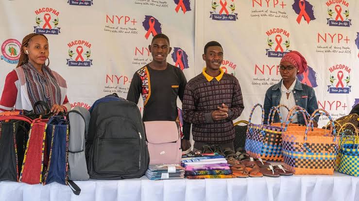Young members of the NYP+ network standing behind a stall of bags, sandals and fabrics they make and sell